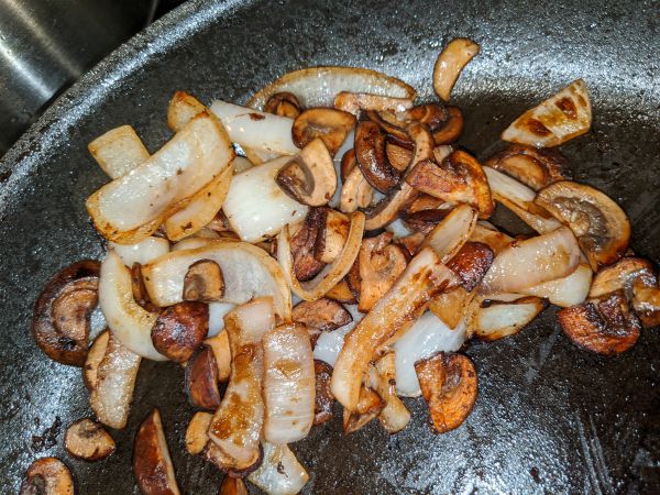 Mushrooms and onions grilling in pan