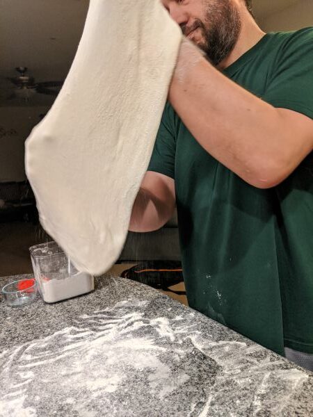 Stretching dough over floured countertop