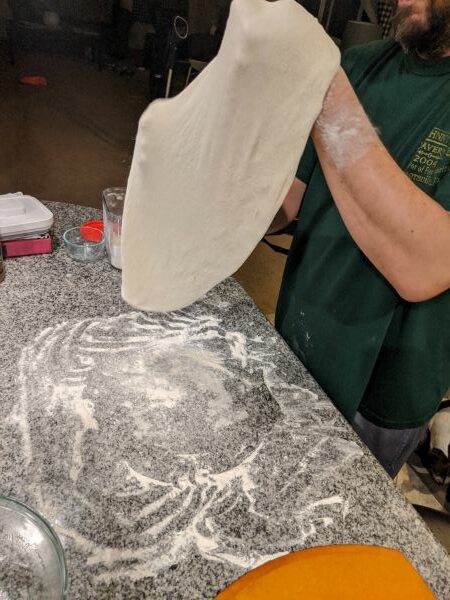 Stretching dough over floured countertop