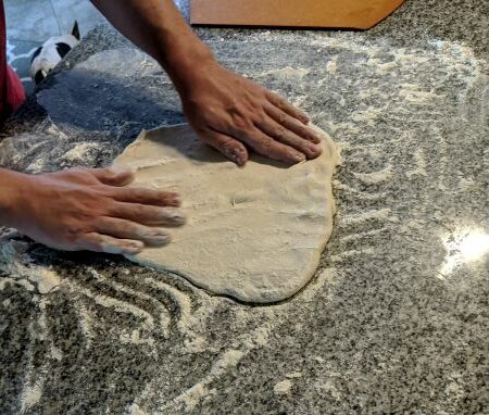 Man Stretching Pizza Dough on floured counter