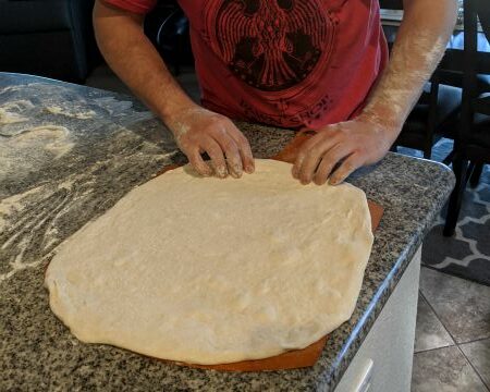 Man Stretching Pizza dough onto tray
