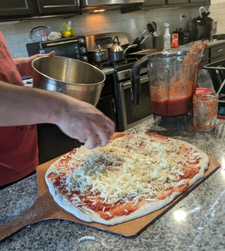 Man adding cheese to pizza