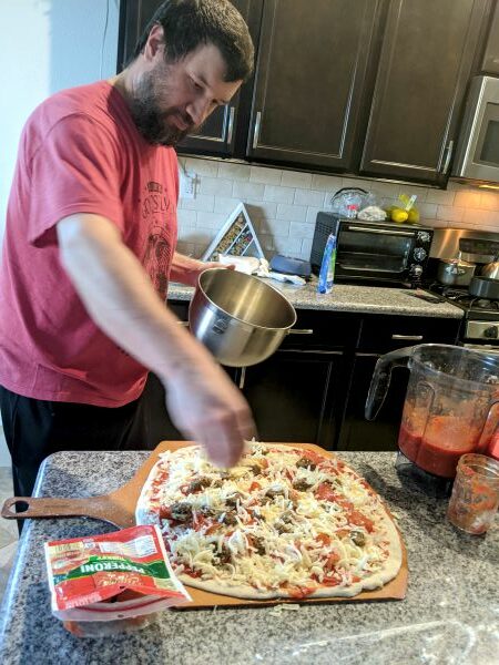 Man putting cheese on pizza