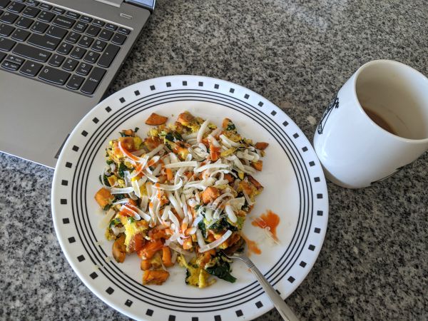 Omelette topped with Cheese, Plated next to coffee and laptop