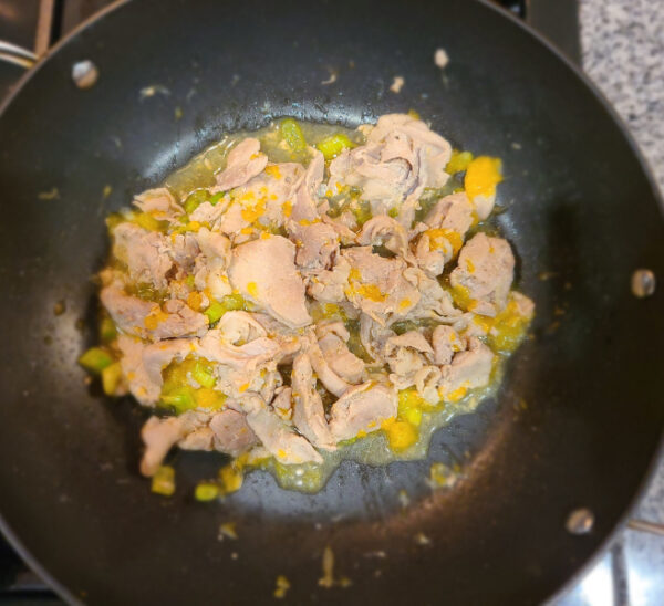 Pork cooking in pan with mandarin oranges