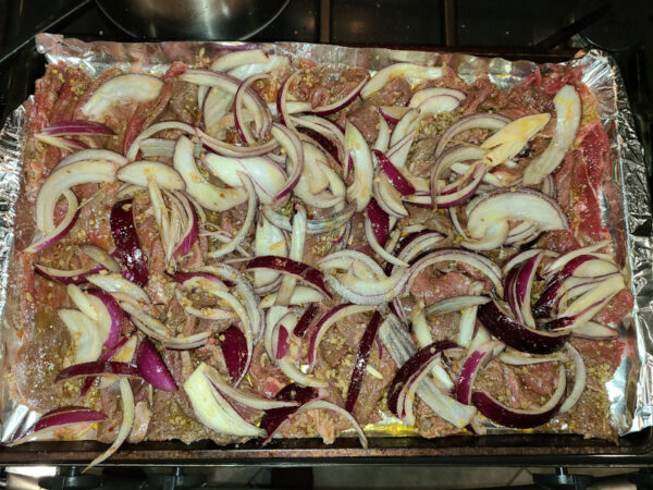 Steak Shawarma and red onions on baking tray