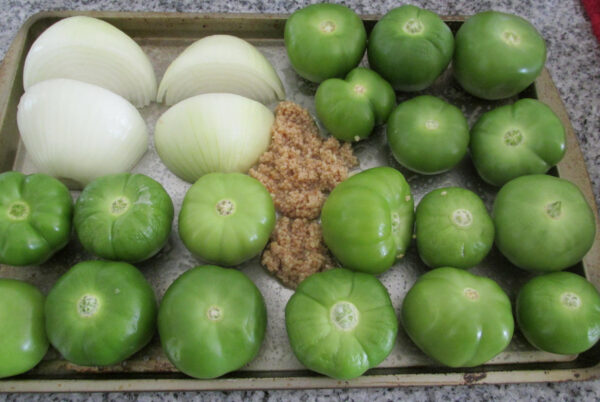 Tomatillos, garlic and onion on baking sheet