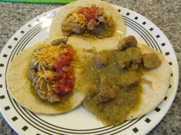 Chile Verde on flour tortillas with salsa and cheese.