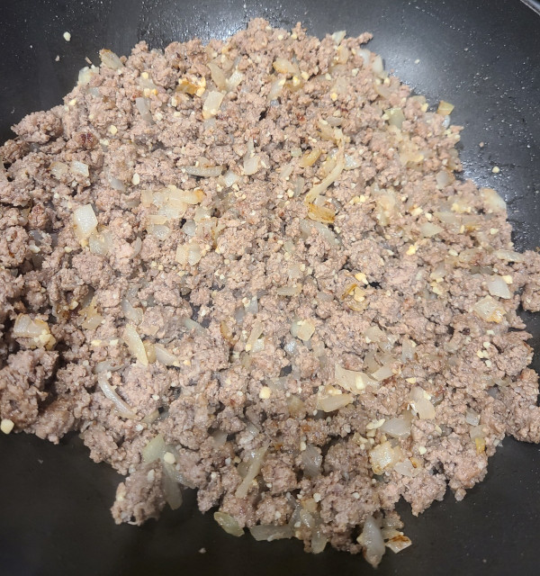 Meat, onions, and minced garlic in pan