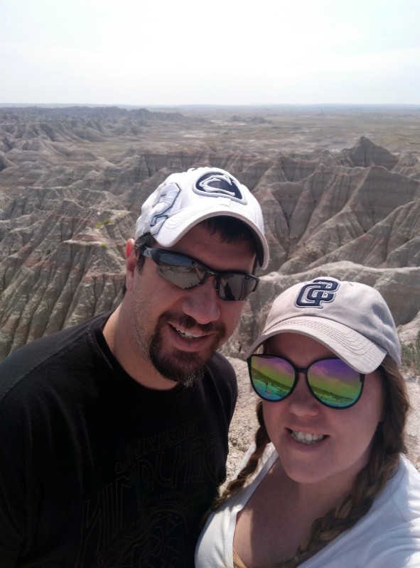Couple taking selfie with Badlands NP in background.