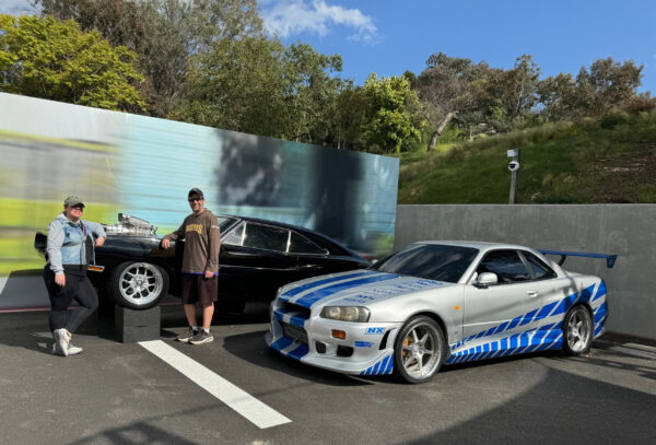 Couple poses with cars from the Fast & the Furious franchise at Universal Studios 60th Anniversary special walk through area at Universal Studios Hollywood
